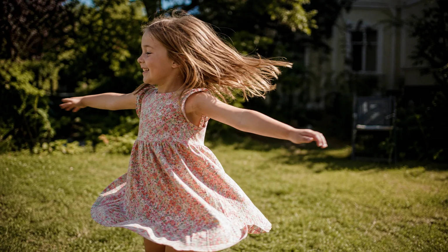 Enfant qui tournoie les bras écartés dans un jardin ensoleillé, mouvement flou, joie sur le visage.