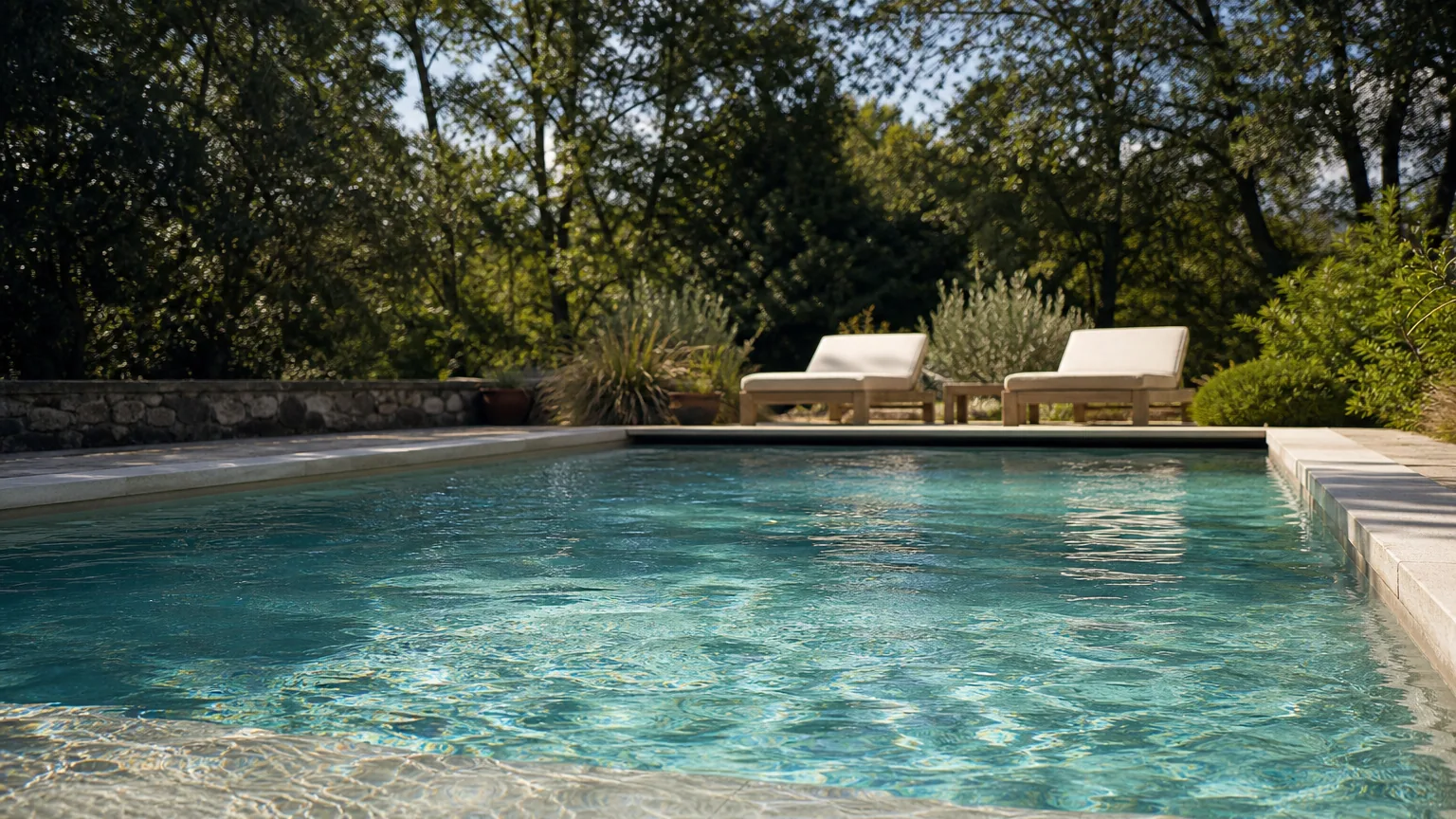 Gros plan d'une piscine extérieure en été, eau turquoise et translucide traversée de reflets de soleil, surface calme et lignes d'eau, sans personne au premier plan.