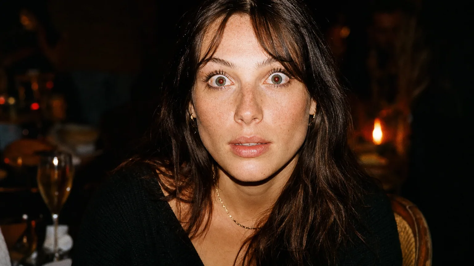 Une femme photographiée de face au flash dans une pièce sombre, avec un reflet rouge visible dans les pupilles.